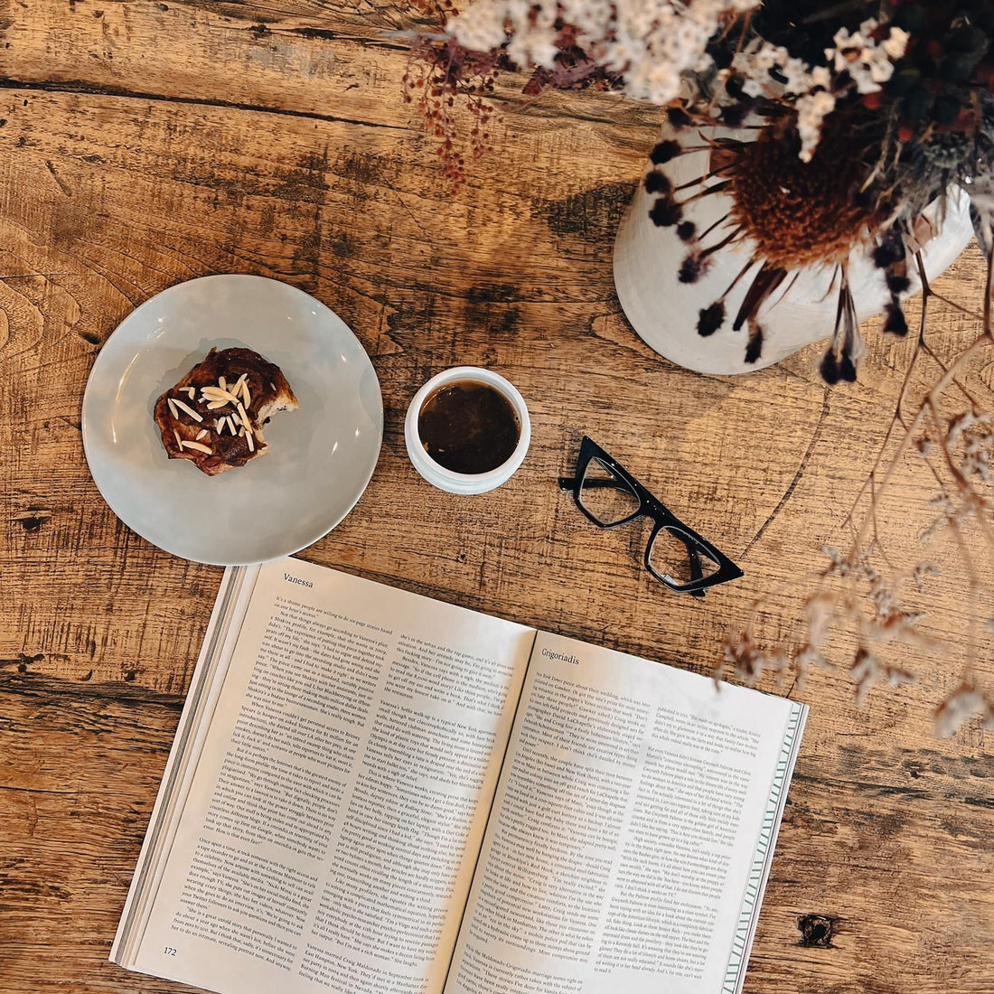 Pair of Daniella reading glasses propped beside a cup of coffee and magazine